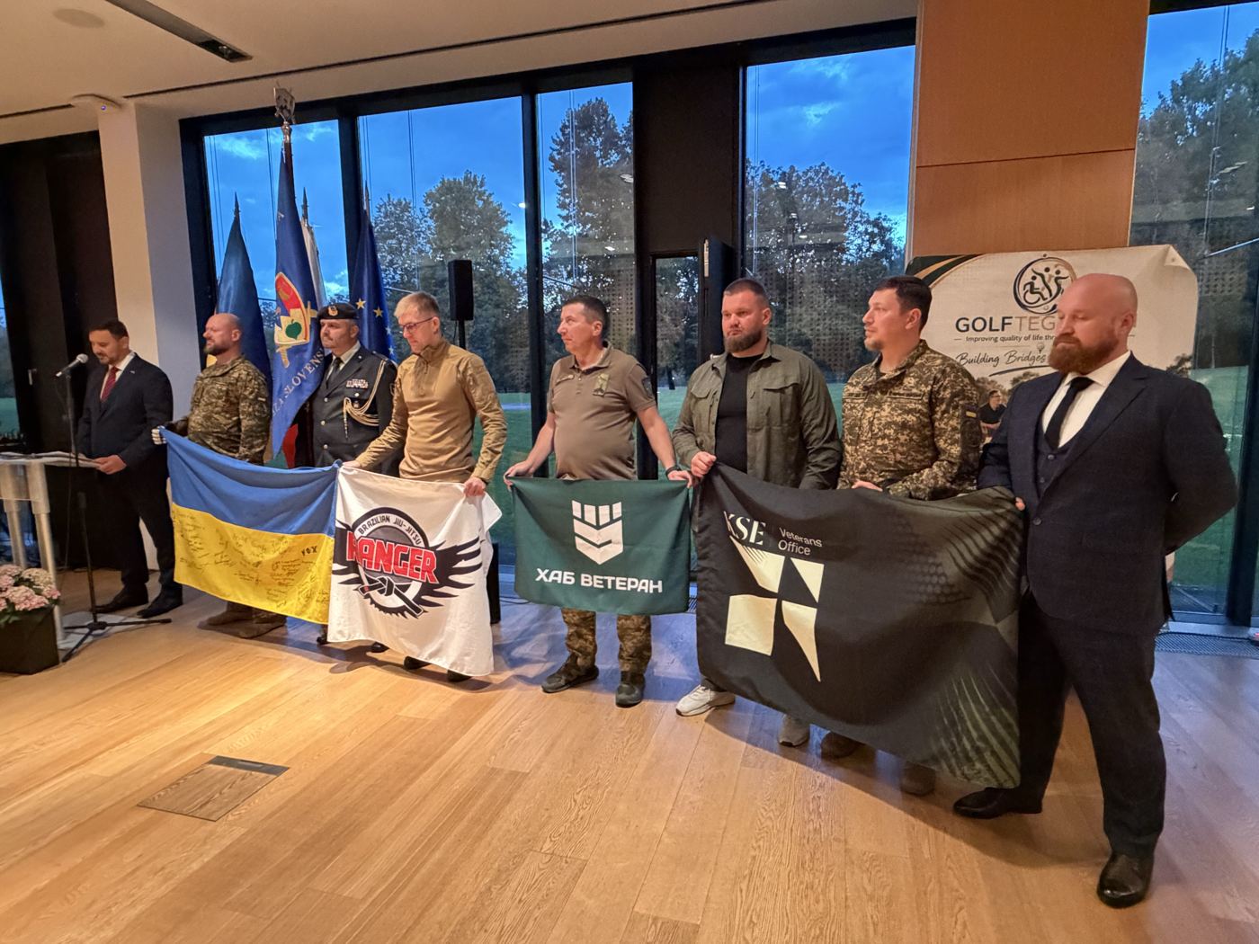 Veterans and partners holding Ukrainian and unit flags at the program evening